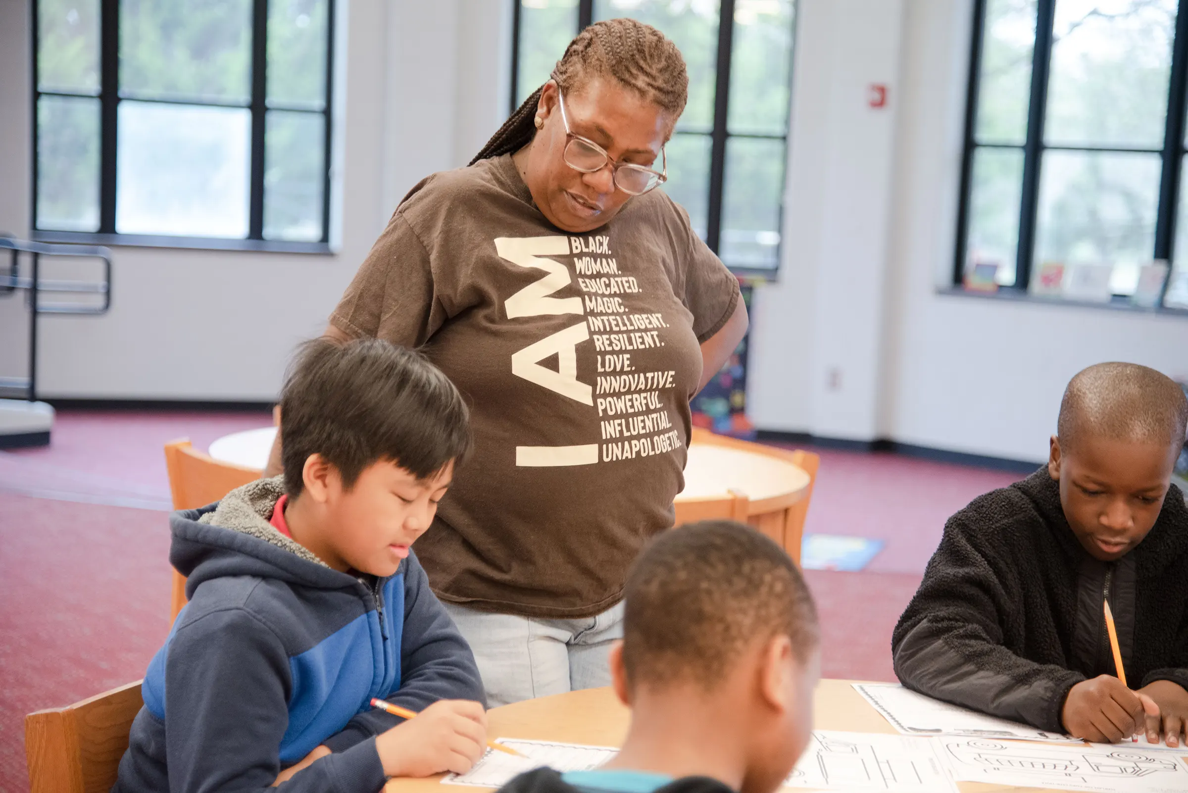 a teacher looking over a table of students with pencils and papers