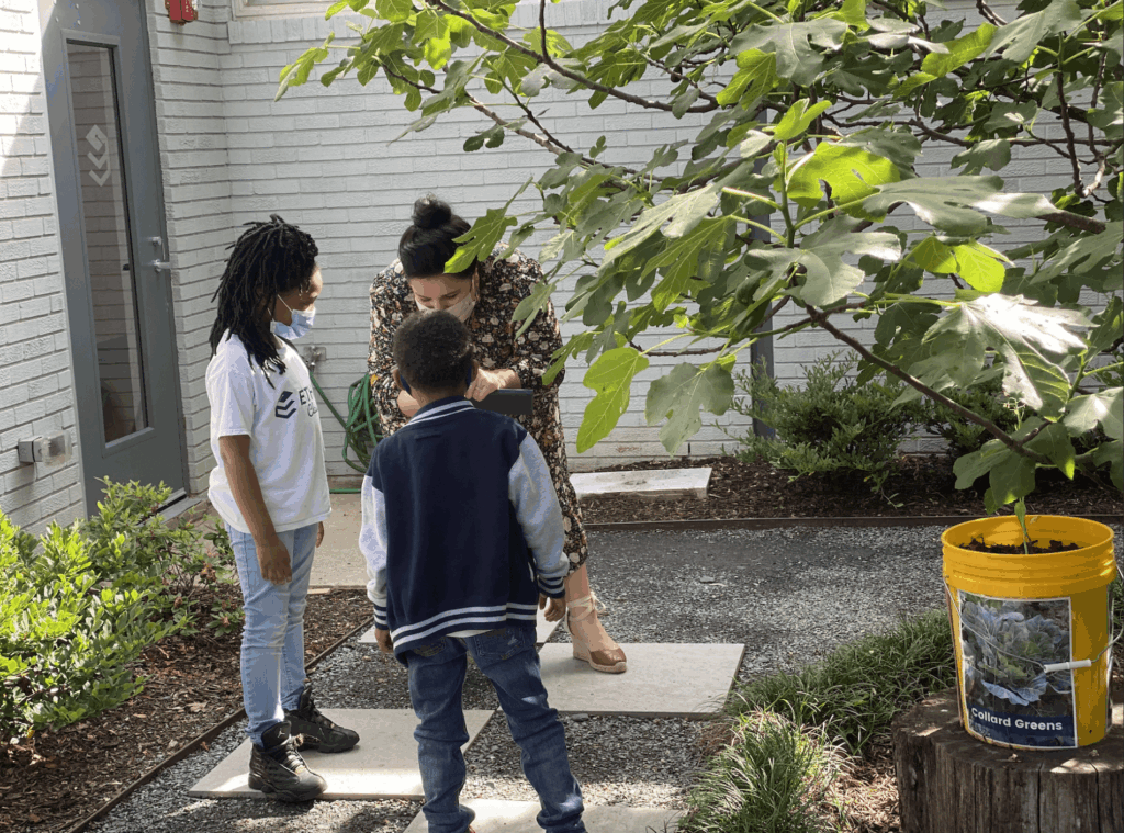 Emily Castilo Leon with two students in the garden