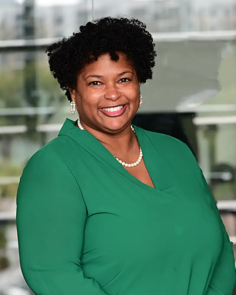 Norledia in a green shirt and pearl necklace, smiling brightly at camera