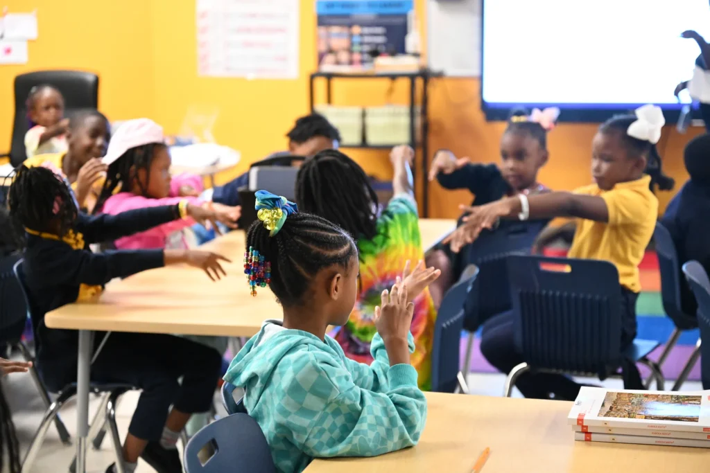 Cheery classroom of young students with their hands up, gesturing